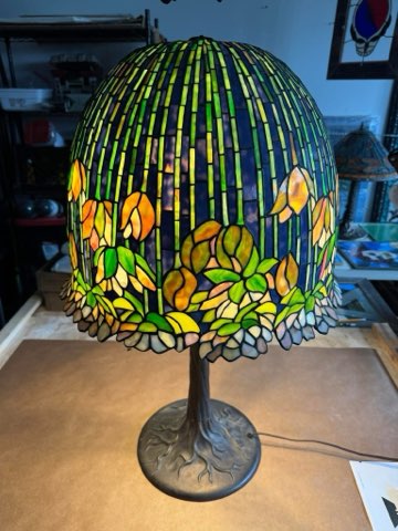 Tall Tiffany-style pond lily lamp in green and amber glass on a bronze tree-root base