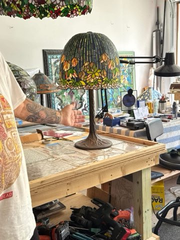 A Tiffany-style lamp sitting on the workbench in Douglas Lang's studio